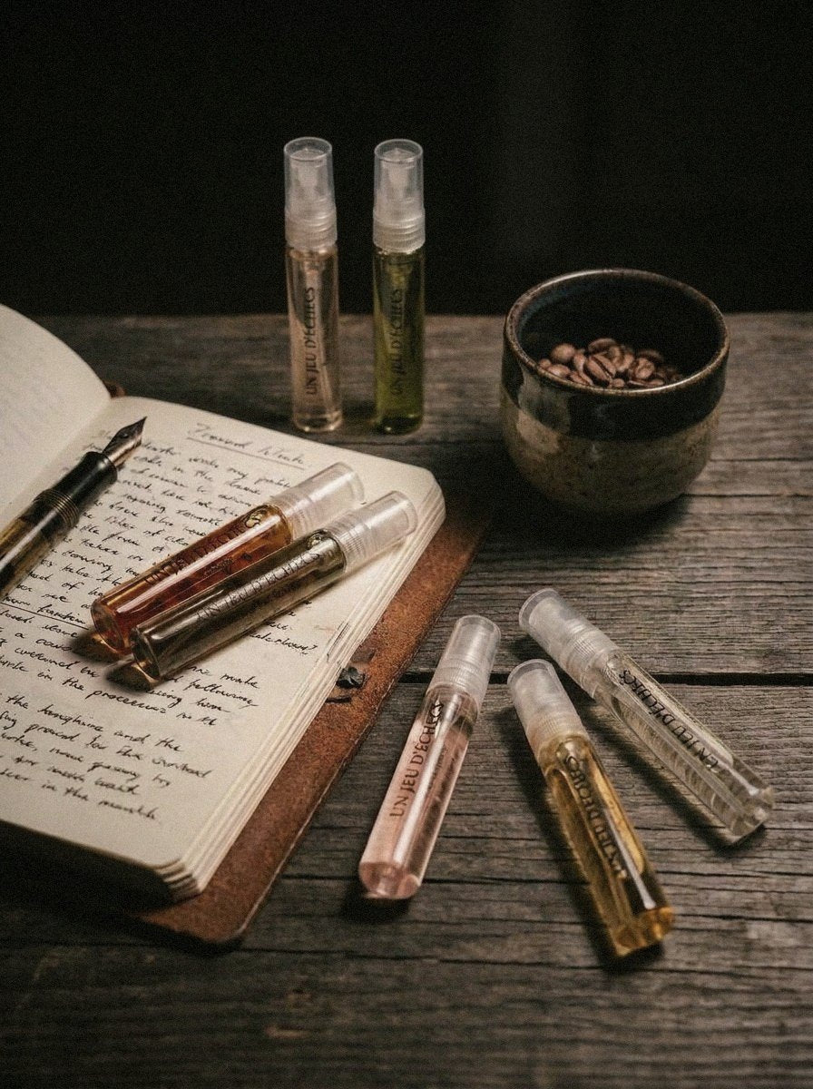 Seven sample vials of different colours on a dark wooden table with an open handwritten notebook and a small ceramic cup of coffee beans